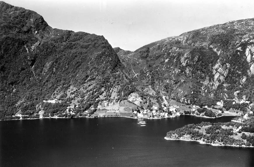 Kyrkje –Bruvik og Indre-Bruvik 1960. Mellom Brøknipa og Olsnessåta til høgre ser ein Trollskaret ved vegen nordover til Brøkdalen.  Foto: Widerøe’s Flyveselskap A/S. 